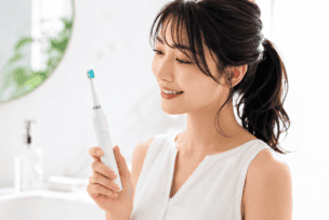 電動歯ブラシを見つめる笑顔の女性